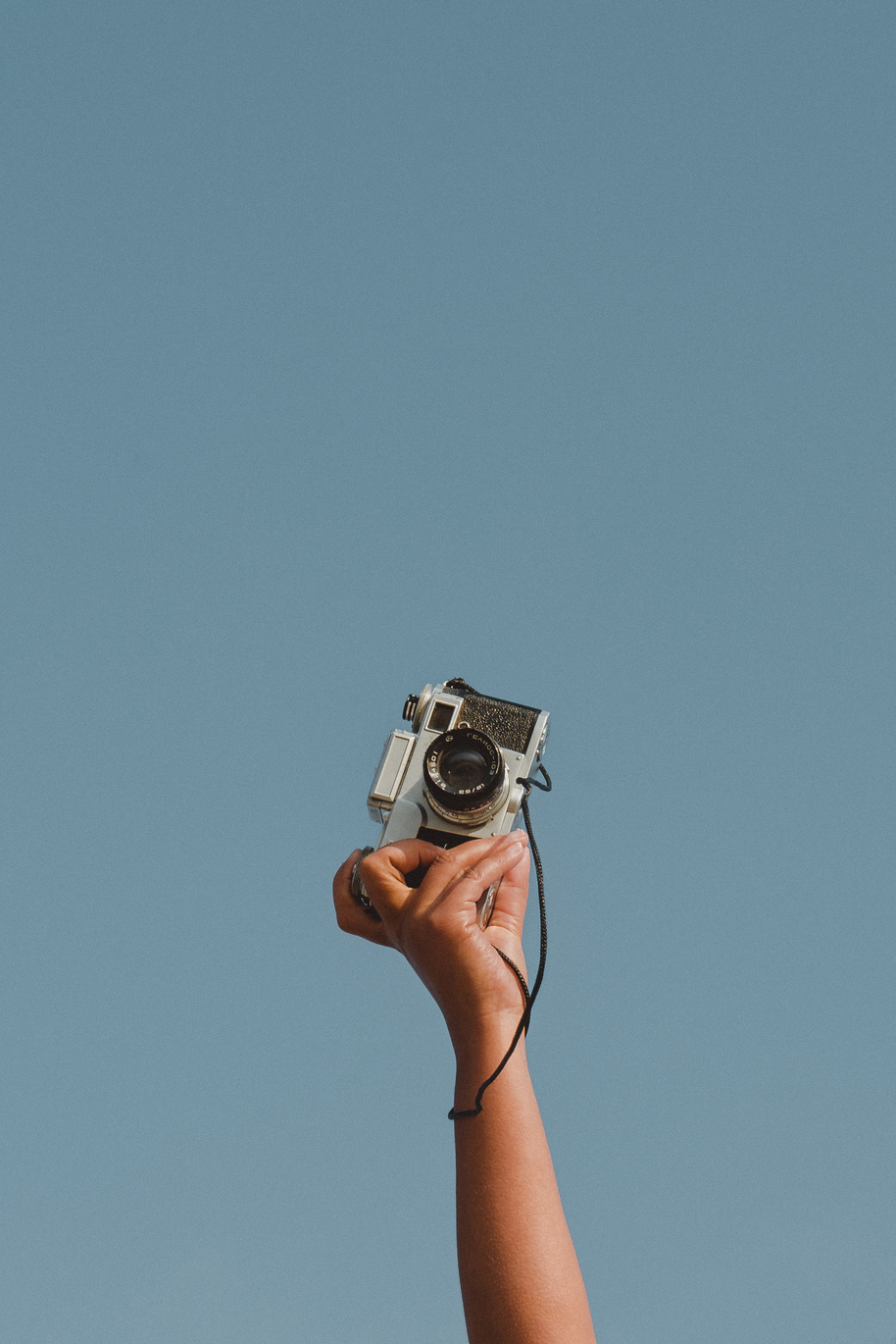 Person's Hand Holding a Vintage Camera against the Sky